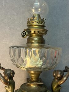 Belle lampe à pétrole ancienne en régule à décor de cariatides, Putti et fleurs, réservoir cristal de Baccarat